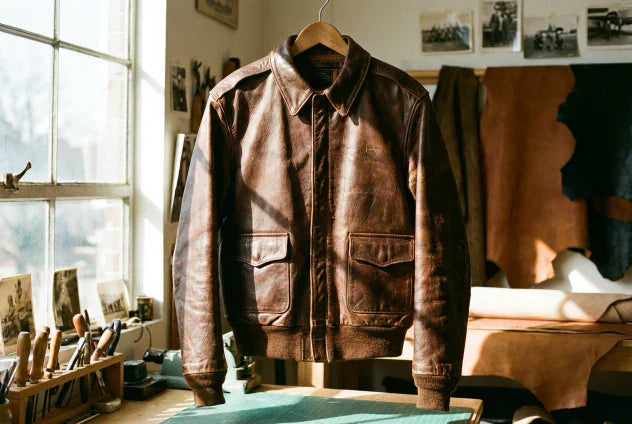 Professionally restored vintage leather jacket hanging in natural light, showing patina and craftsmanship details